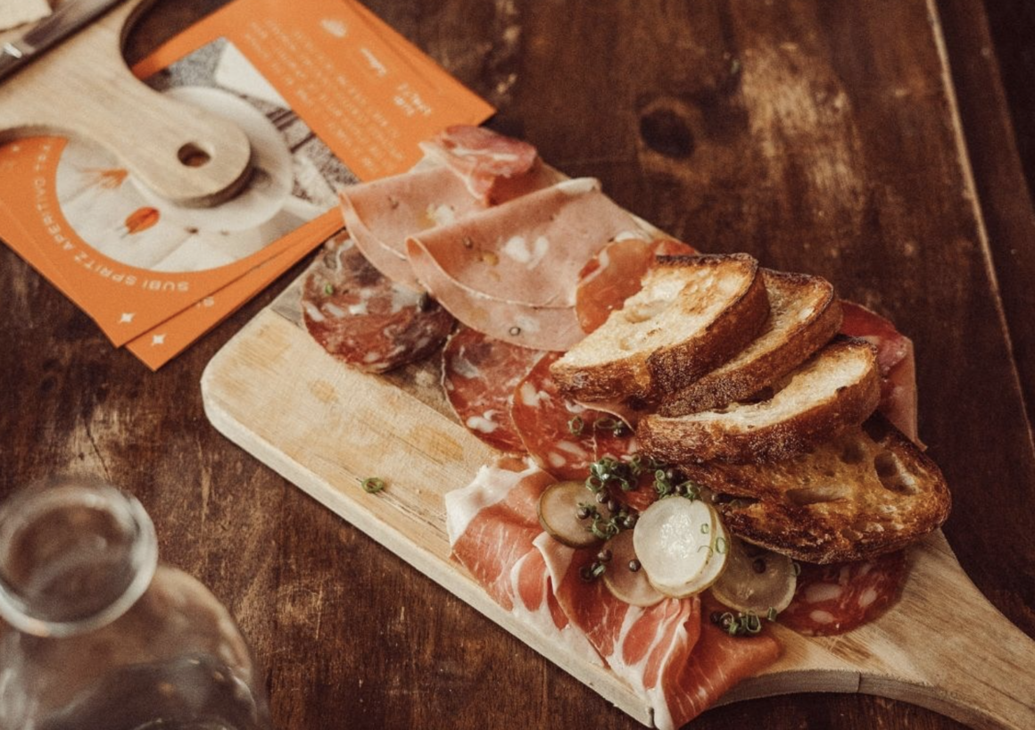 A charcuterie board sits on a wooden paddle on a table